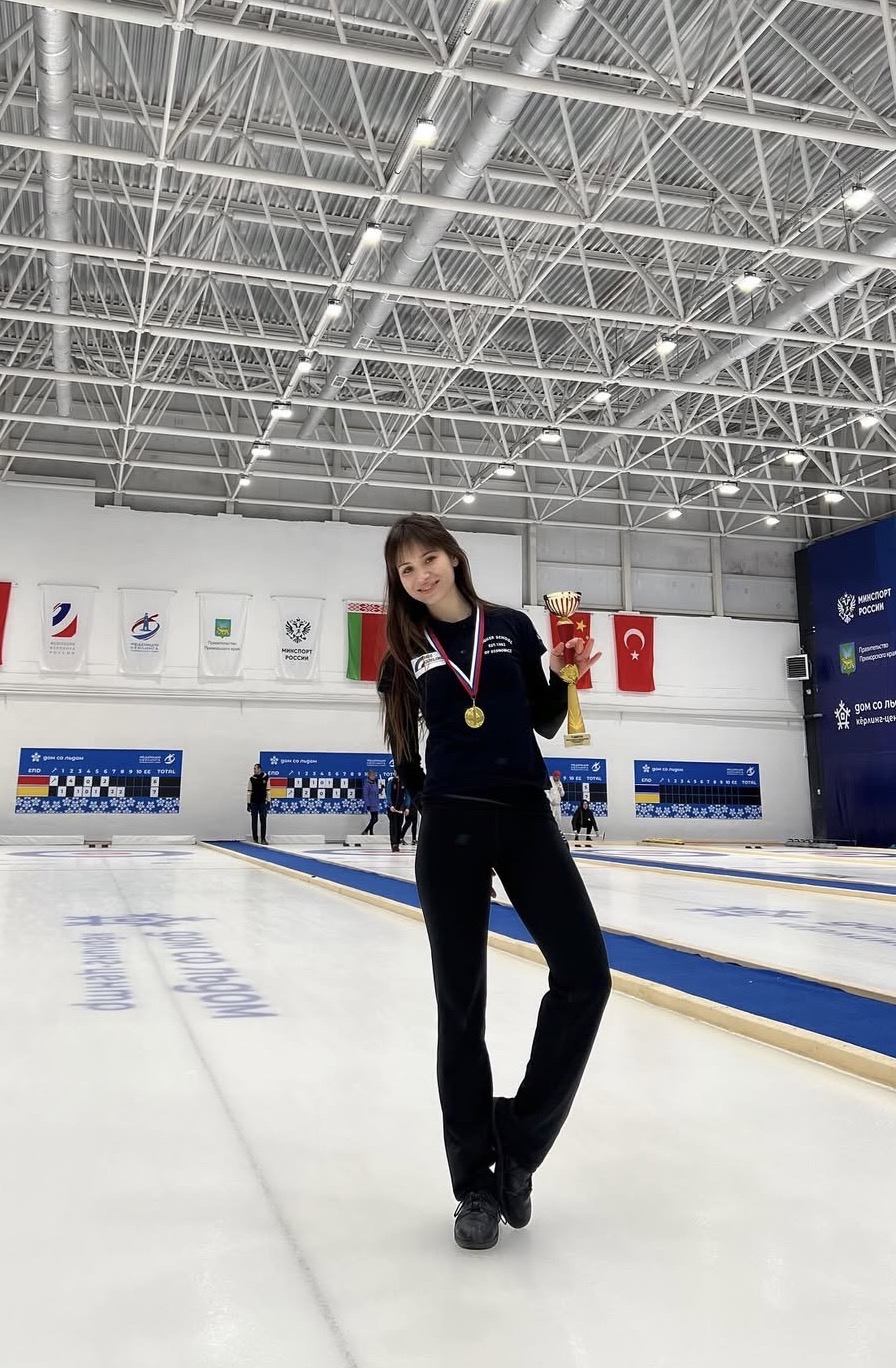 Sabina Kosimova holding a trophy at a curling competition